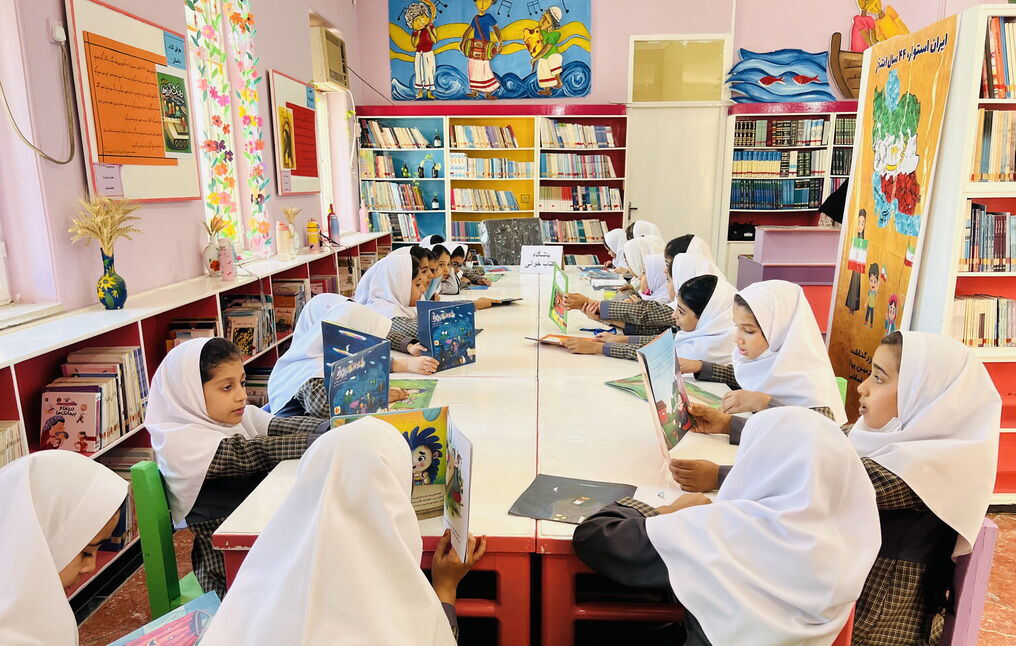 گروهی از دانش‌آموزان دختر در حال مطالعه کتاب در کتابخانه مدرسه