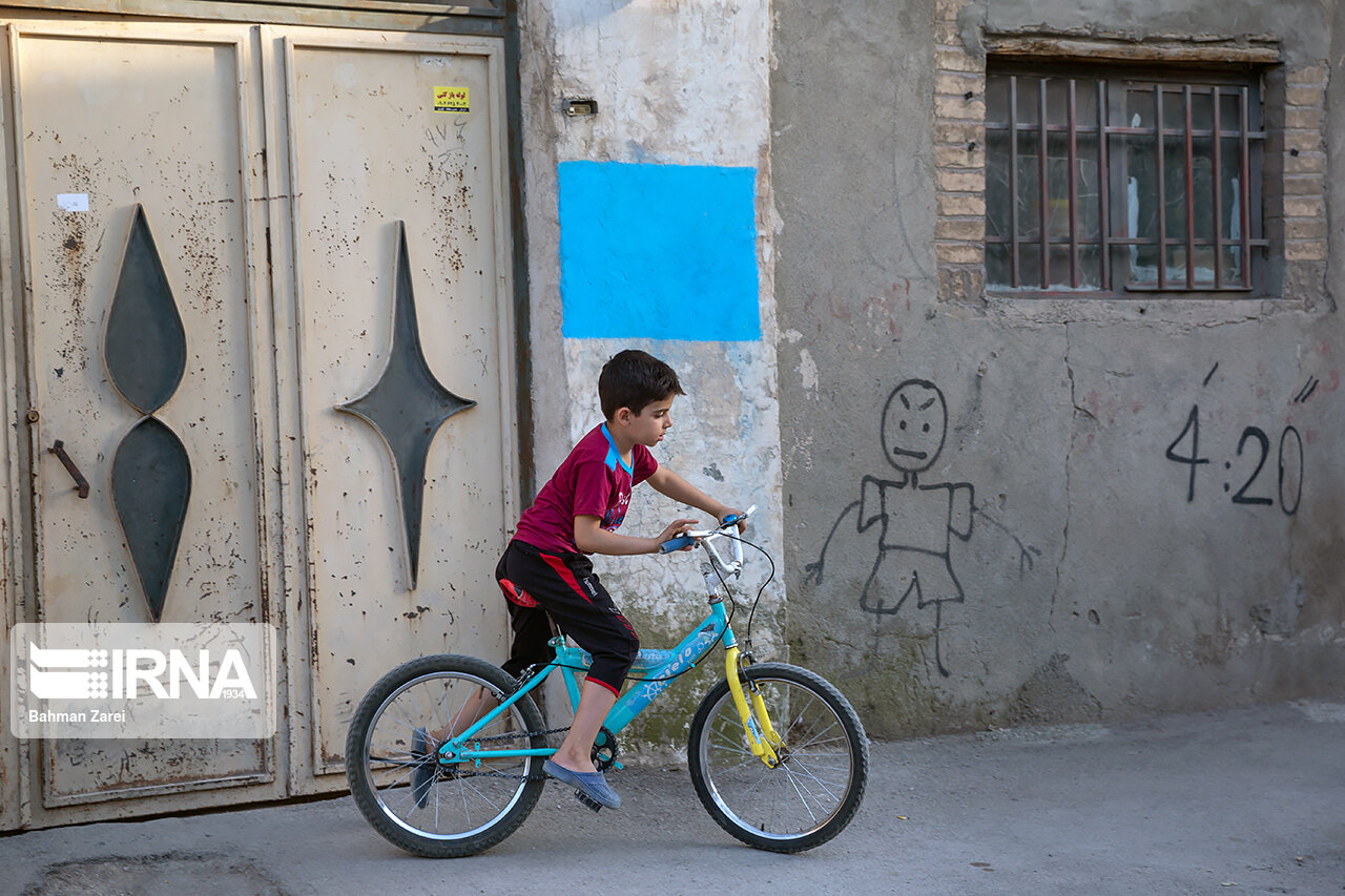 کودکی در محله جوانشیر کرمانشاه در حال دوچرخه سواری