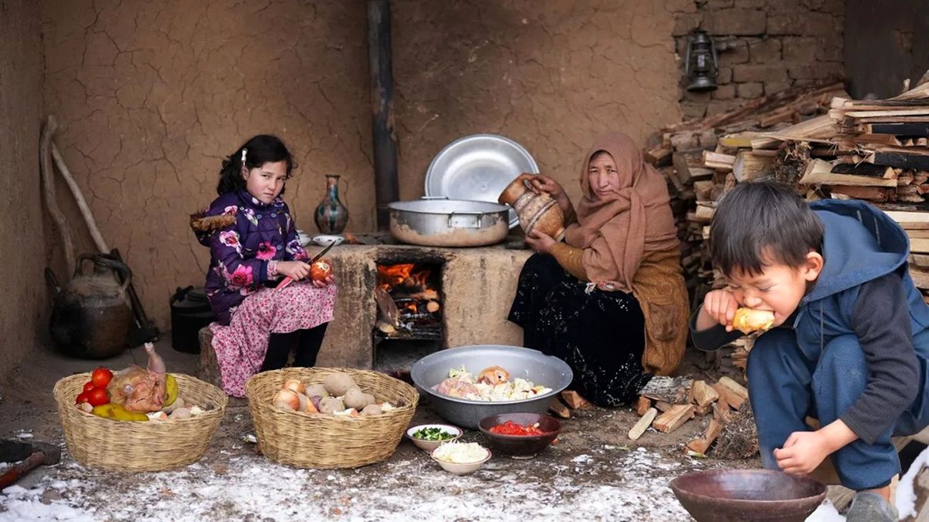 یک زن افغانستانی در حال پخت غذا در آتش‌خانه